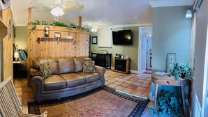 A cozy living room with a leather sofa, a wooden wall shelf, a television, and a fireplace. - Beautiful view,18 acres,pool, game room,Axis deer, 3 mile’s to the  river trail! (Kerrville)