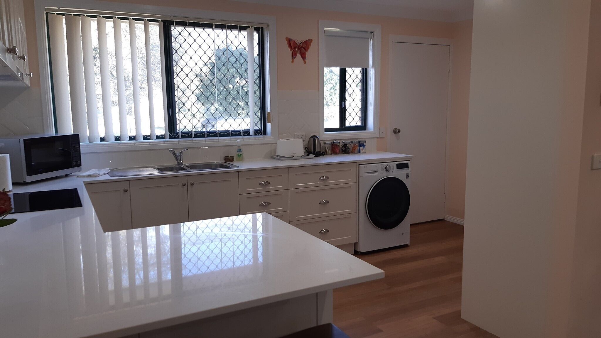 A compact kitchen with a microwave, sink, and washing machine.