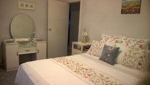 A bedroom with a bed, a dresser, a mirror, a nightstand, and a lamp. - Butterfly Cottage - Pet Friendly Tumut (Tumut)