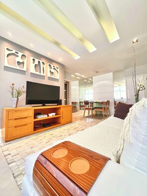 A modern living room with a flat-screen TV, wooden entertainment unit, and a dining area with chairs and a table. - LEBLON / CLEAN AND SOPHISTICATED DESIGN, BEST LOCATION, MODERN CONDOMINIUM  (Rio de janeiro)