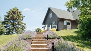 Una casa residencial con una escalera que lleva a la puerta principal, rodeada de un césped cuidado y plantas de lavanda.