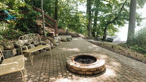 Un patio empedrado con un hogar, mobiliario exterior y una escalera que lleva a una terraza.