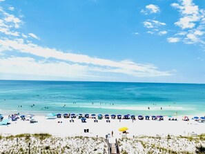 A beach with white sand, clear blue water, and umbrellas. - GULF VIEW LUXURIOUS CONDO,BEACH SERVICE,10% WEEKLY/MEMBER DISC. TENNIS/PICKLE CT (Okaloosa Island)