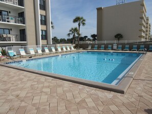 A swimming pool with lounge chairs and a tiled deck. - GULF VIEW LUXURIOUS CONDO,BEACH SERVICE,10% WEEKLY/MEMBER DISC. TENNIS/PICKLE CT (Okaloosa Island)