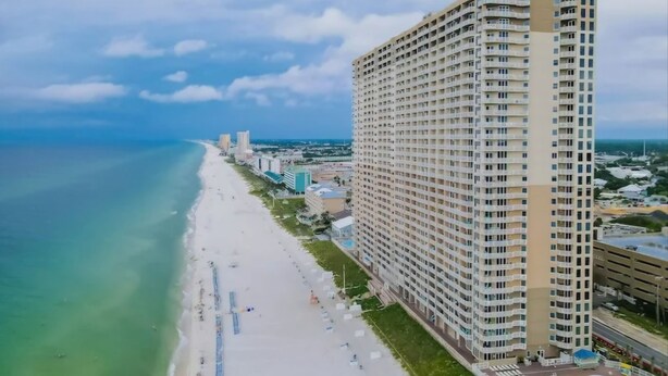 A high-rise hotel with a beach view, multiple floors, and a swimming pool.