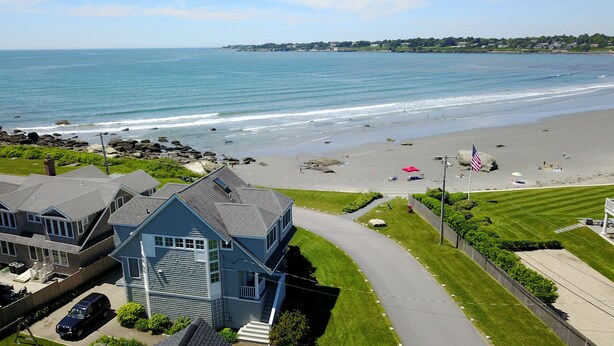 A coastal residential area with a beach, houses, and a clear view of the ocean.
