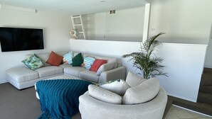 A modern living room with a sectional sofa, a round armchair, a blue throw blanket, and a potted plant.