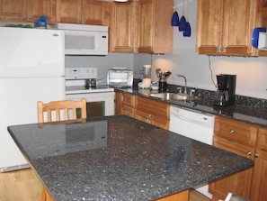 Compact kitchen with refrigerator, microwave, toaster, and dishwasher, perfect for meal preparation.