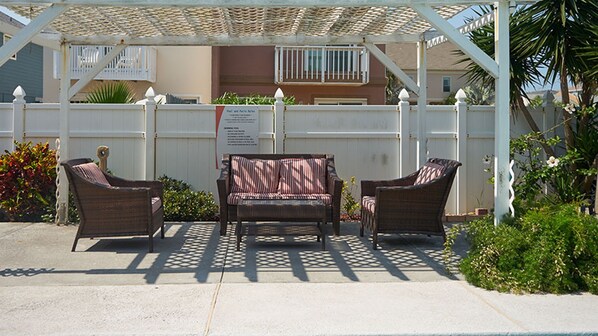 A covered outdoor seating area with wicker furniture and a pergola.