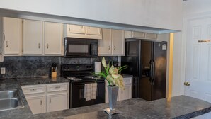 Una cocina moderna con armarios blancos, una estufa negra, un microondas y un refrigerador.