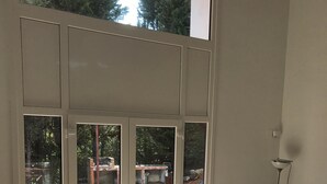 Une pièce dotée d’une grande porte-fenêtre coulissante qui donne sur un espace extérieur. À l’intérieur, on trouve une table entourée de chaises, dont certaines sont agrémentées de coussins en forme d’étoile.