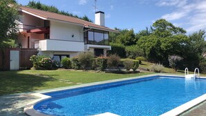 Une maison à deux étages avec une piscine dans le jardin.