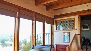 A bedroom with a wooden ceiling, a bed with a floral bedspread, a dresser, and a staircase.