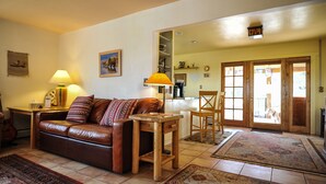 A living room with a brown leather sofa, two lamps, a wooden side table, and a patterned rug.