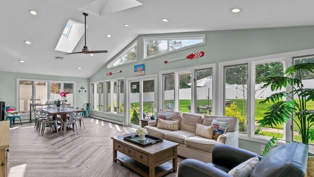 Un salon spacieux avec un haut plafond, de grandes fenêtres, un coin repas et un espace salon confortable.