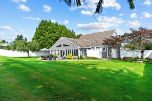Une maison à deux étages avec un grand jardin à l’avant, une terrasse couverte et un garage.