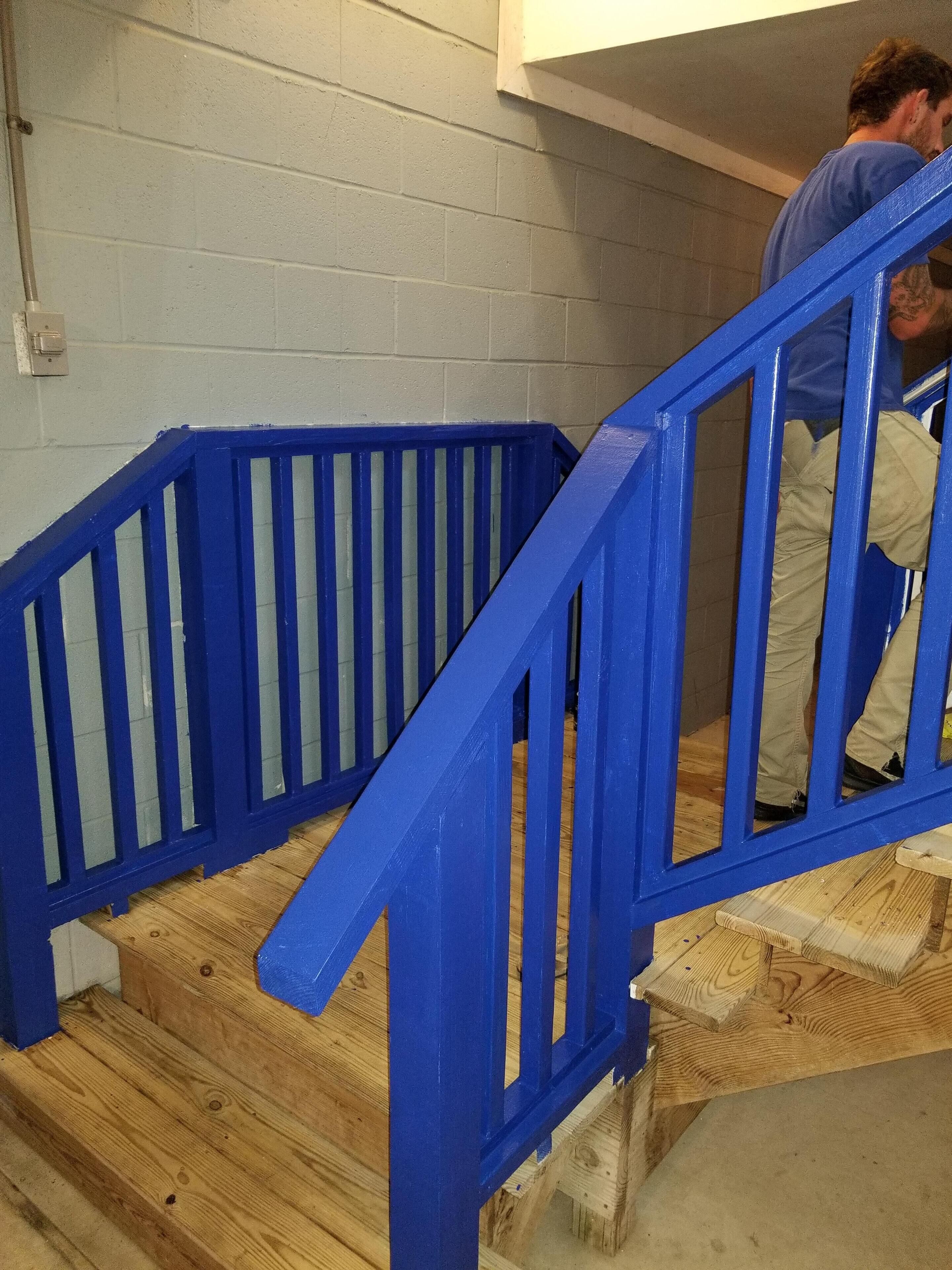 Een houten trap met blauwe leuningen.