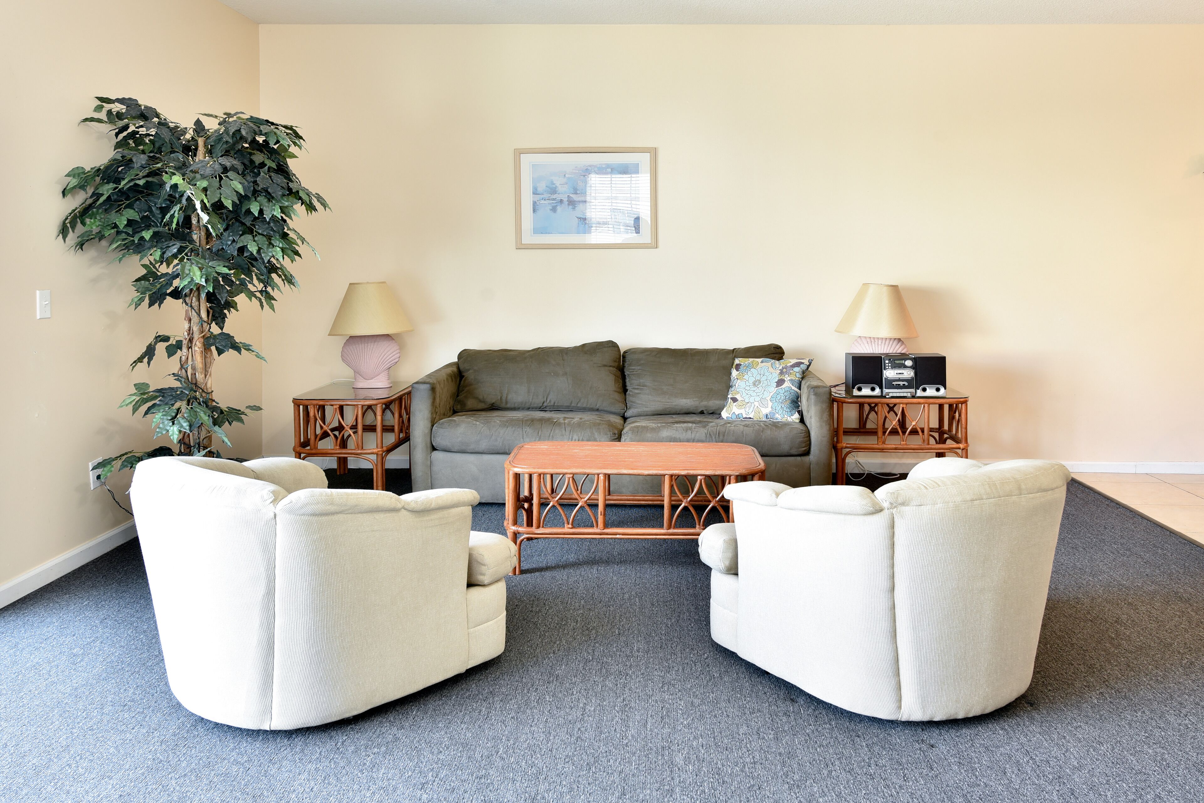 A living room with a sofa, two armchairs, a coffee table, a floor lamp, a side table, and a potted plant.