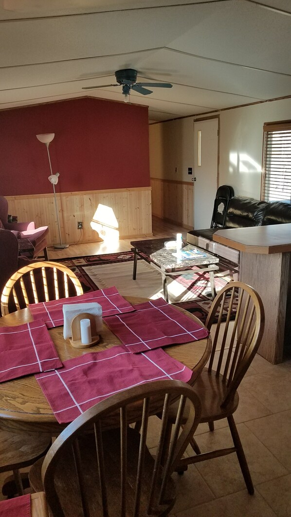 A dining area with a wooden table, chairs, and a ceiling fan.