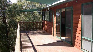 A wooden deck with a green awning, a glass door, and a window with blinds.