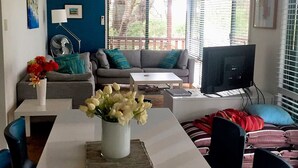 A living room with a white table, grey sofa, and a TV.