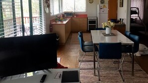 A compact kitchen with a dining area, a TV, and a clock on the wall.