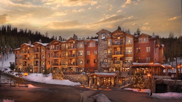 A multi-story lodge with a stone facade, multiple balconies, and a snow-covered landscape. - Ski in, Ski out, luxury resort. Exceptional snow (Truckee)