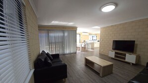 En moderne stue med en sort sofa, et træbord og et fjernsyn på et træstel.
