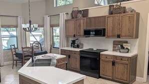A modern kitchen with wooden cabinets, a black microwave, and a built-in oven. - Stunning Indoor & Outdoor Living near Beach and Shopping. Close to Boca Raton (Deerfield Beach)