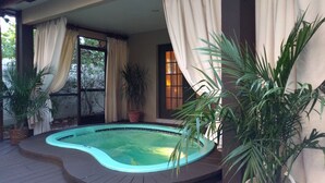An outdoor swimming pool area with a hot tub, surrounded by potted plants and curtains. - Stunning Indoor & Outdoor Living near Beach and Shopping. Close to Boca Raton (Deerfield Beach)