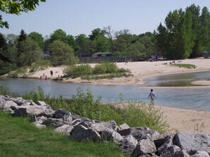 Une vue sur la rivière, avec une plage de sable, des rochers et de la végétation.