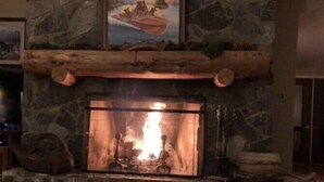 A stone fireplace with a log fire, a stone mantle, and a painting above it. - Hickory Hill Mountaintop charming family friendly quiet very private lake view (Bolton Landing)