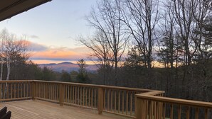 A wooden deck with a railing, overlooking a forested area and distant mountains. - Hickory Hill Mountaintop charming family friendly quiet very private lake view (Bolton Landing)