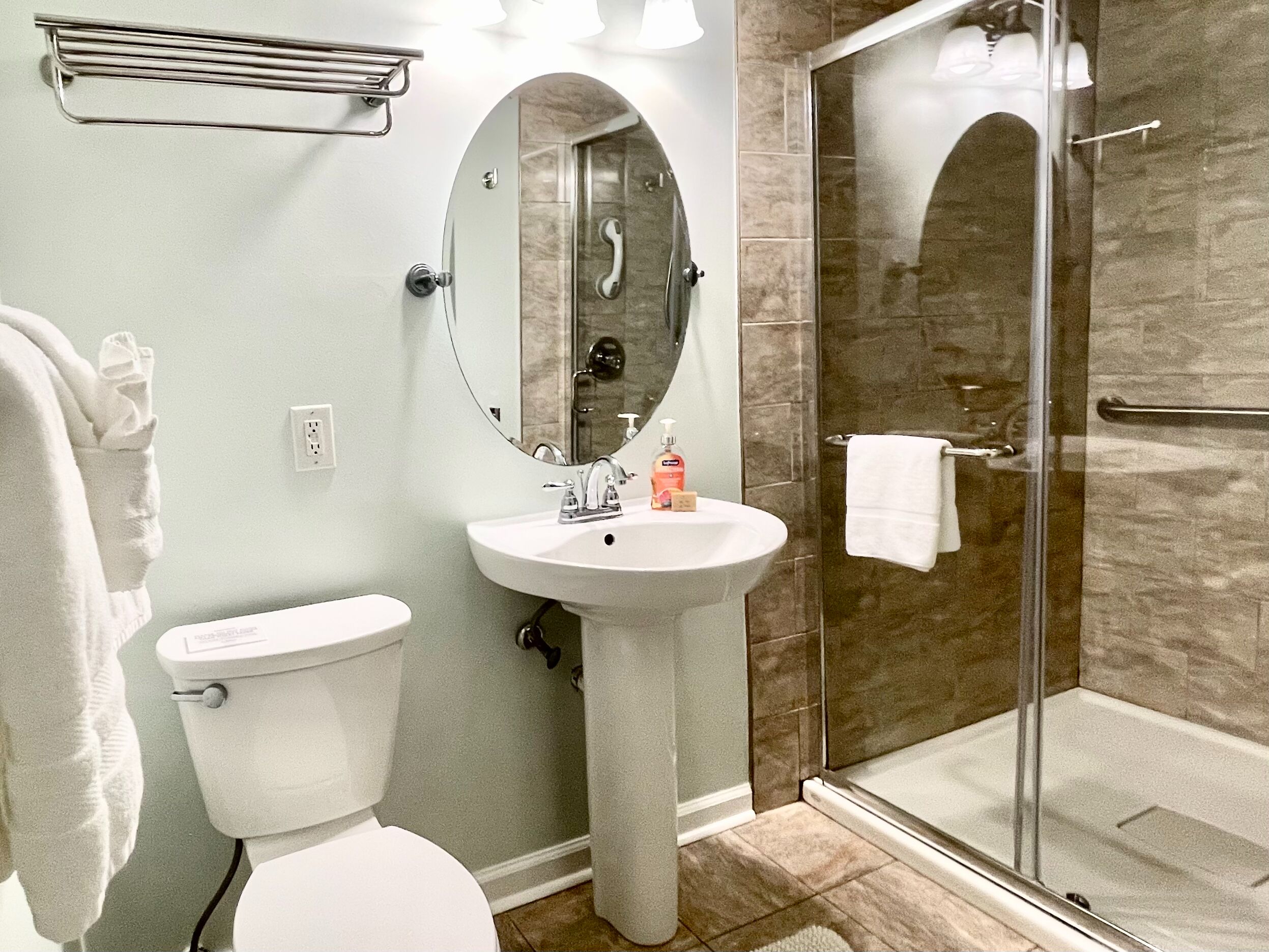 Ein Badezimmer mit Toilette, Waschbecken und einer Dusche mit Glaswand.
