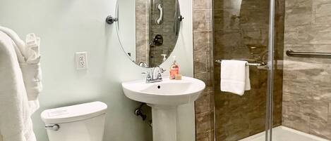 A bathroom with a toilet, sink, and glass-enclosed shower.