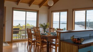 Un comedor con muebles de madera, ventanas amplias y vista al mar.