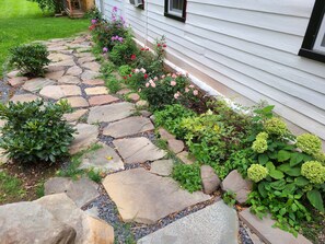 A stone pathway leading to a house with a garden.
