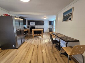 A compact kitchen with a refrigerator, microwave, wooden table, and chairs.