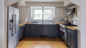 Eine Küche mit dunklen Schränken, einem Edelstahl-Kühlschrank, einer doppelten Spüle und einer Holz Arbeitsplatte.