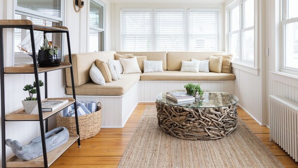 Ein gemütliches Wohnzimmer mit einem beigen Sofa, einem Glastisch und einer Holzregaleinrichtung.