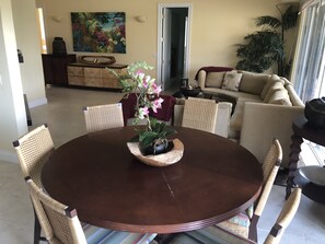 A dining area with a round table, six chairs, and a centerpiece of pink flowers.