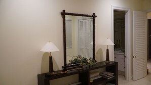 Una consola de fusta fosca amb dues làmpades, un mirall i una petita planta.