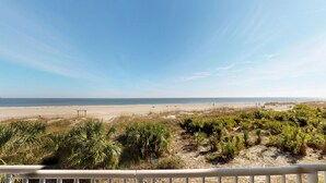 A beach view with a railing in the foreground, sandy beach, and ocean in the background. - Beachfront Luxury 1 BR Condo - 3 Oceanfront Pools (Tybee Island)