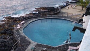 Une piscine circulaire offrant une vue sur l’océan et le rivage rocheux.