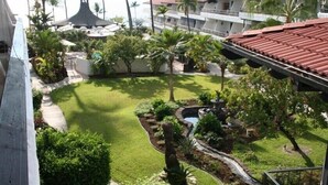 Une cour d’hôtel avec une piscine, des palmiers et une vue sur l’océan.