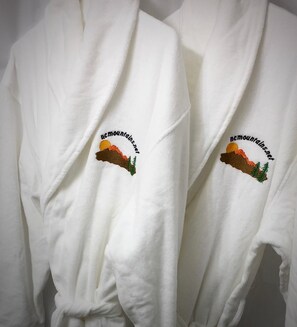 Two white robes with embroidered mountain logos and text.