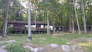 A cabin with a wooden deck and a hammock in a forested area. - Rustic Mountain Lakefront Cottage  (Scottsboro)