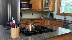 Une cuisine avec des meubles en bois, un réfrigérateur en acier inoxydable, un four à micro-ondes, une cuisinière et une fenêtre.