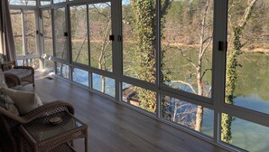 A room with large windows overlooking a lake, wicker furniture, and a wooden floor. - Wonderful home with dock on Tellico Lake (Loudon)