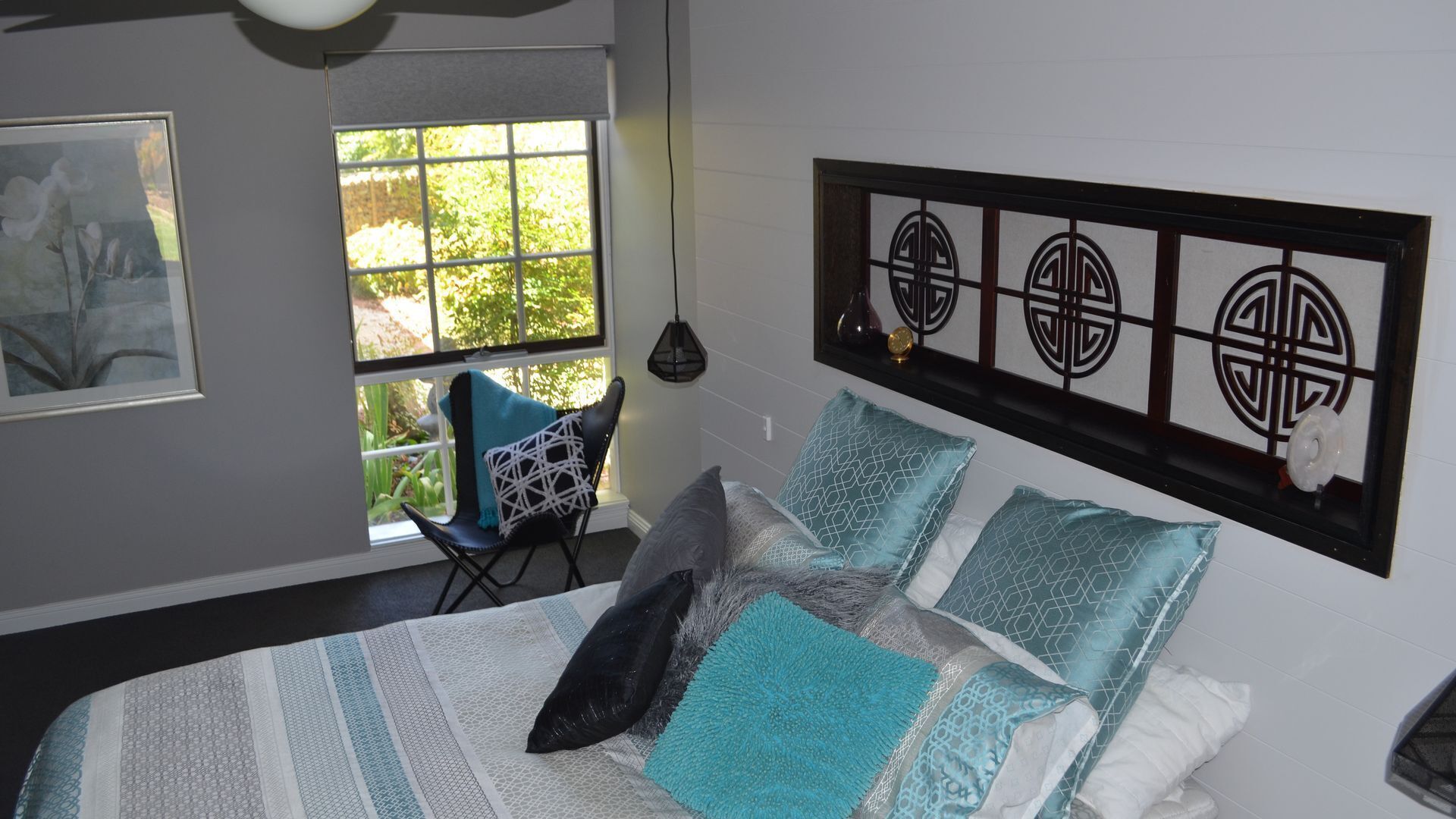 Une chambre à coucher comprenant un lit, une chaise, une fenêtre et un mur orné de panneaux décoratifs.